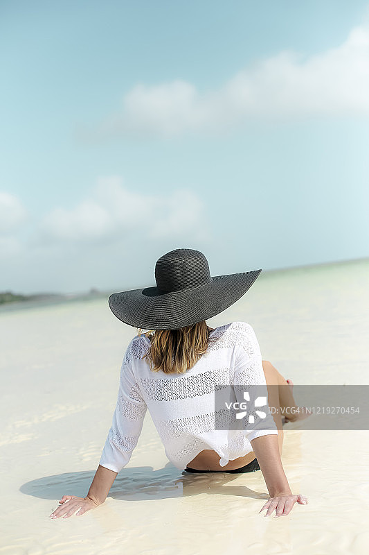 戴着夏日帽子的女孩在美丽的热带海滩上图片素材