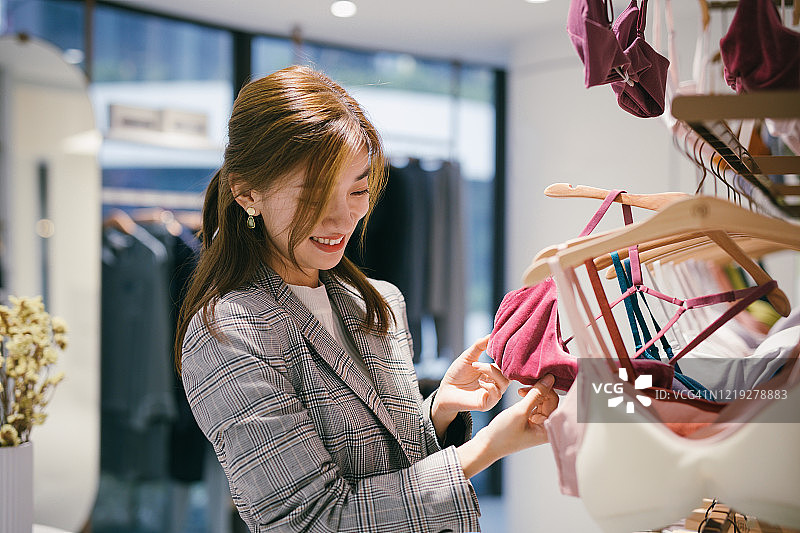 年轻的亚洲女性在服装店选择新的文胸图片素材