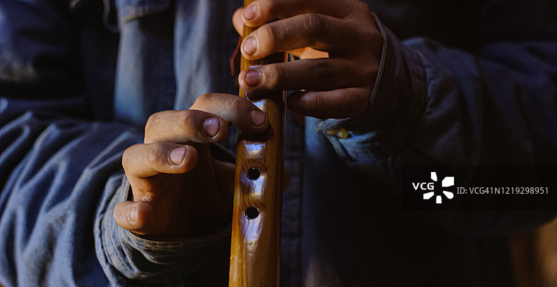 在霍根（纳瓦霍小屋）里演奏纳瓦霍长笛的美国原住民少年图片素材