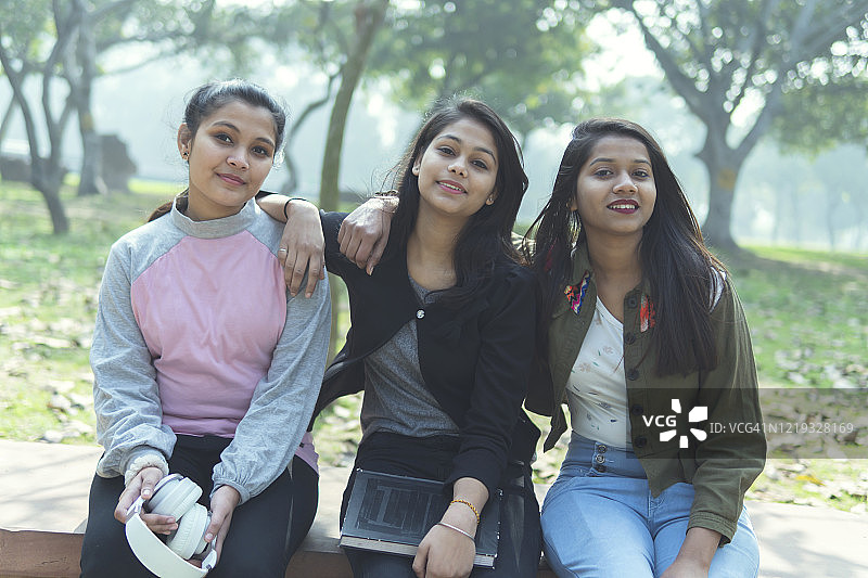 多民族女性朋友坐在公园长椅上享受大自然图片素材