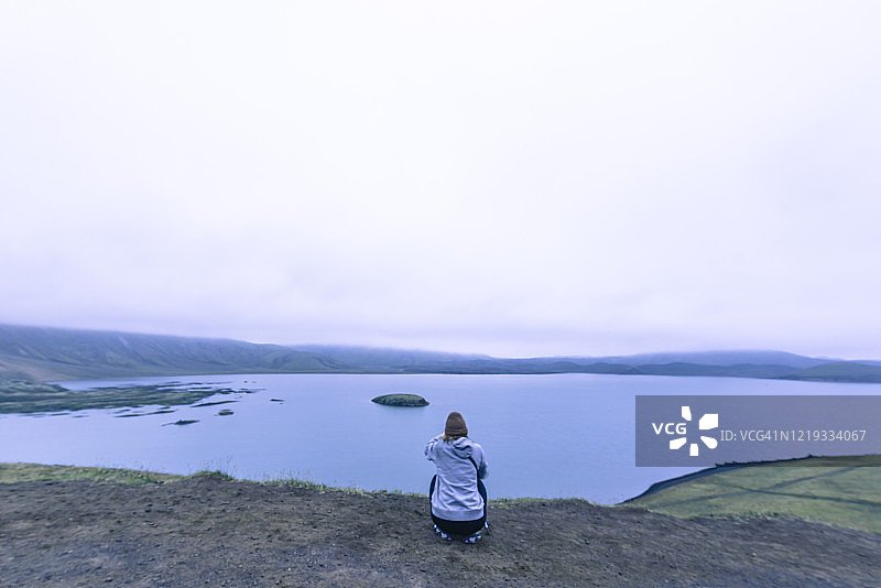日落时分，女人在冰岛高地拍摄湖景图片素材