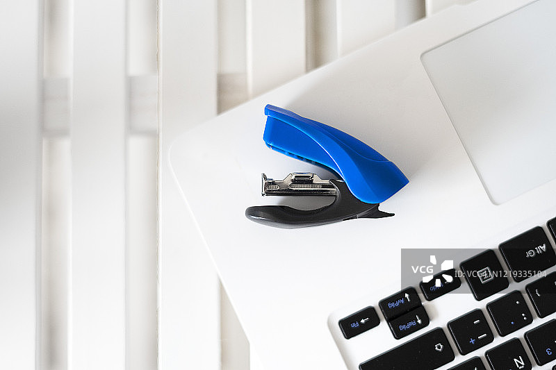 白色笔记本电脑上的蓝色订书机图片素材