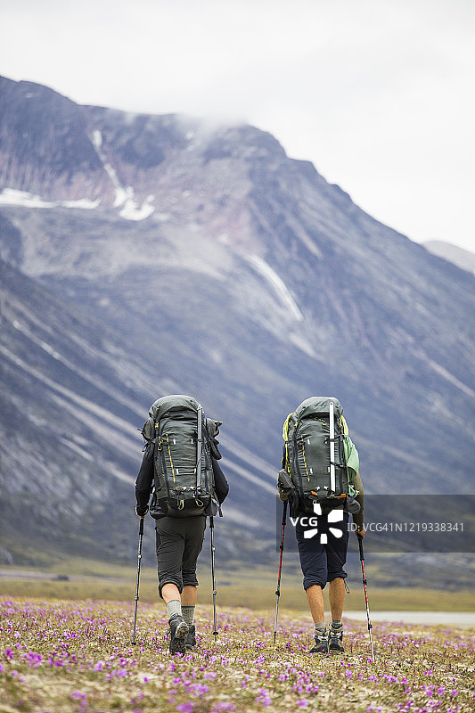 巴芬岛偏远地区徒步旅行的两个背包客背影图片素材