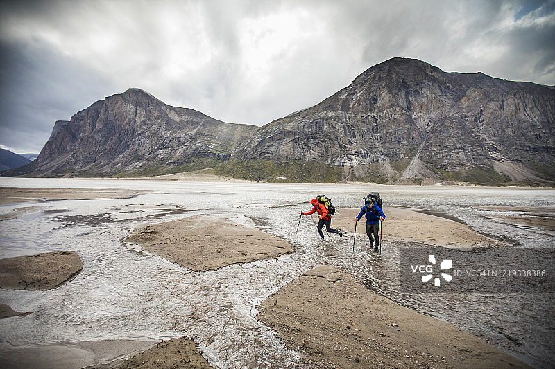 两个背包客在阿克夏亚克山口穿越河流图片素材