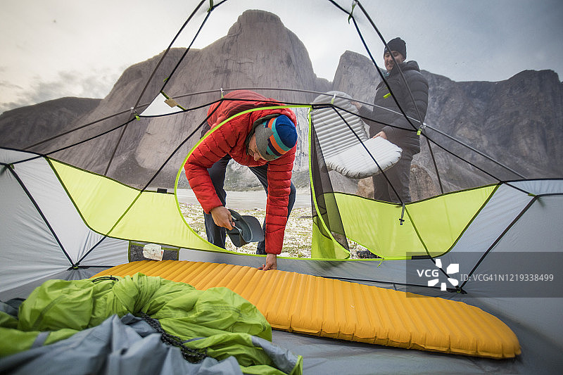 两个男人在攀岩旅行中于帐篷内铺设睡垫图片素材
