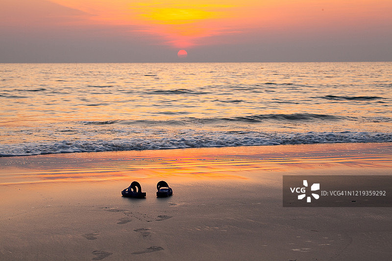 夕阳下海滩上的一双拖鞋，拍摄于泰国桐艾府Hat Ban Chuen海滩图片素材