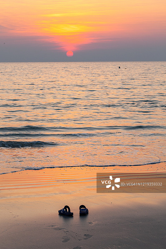 夕阳下海滩上的一双拖鞋，拍摄于泰国桐艾府Hat Ban Chuen海滩图片素材