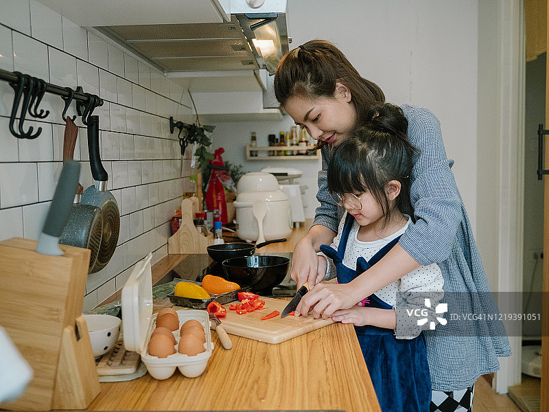 千禧一代母亲在厨房准备早餐，女儿帮忙在家烹饪煎蛋卷图片素材