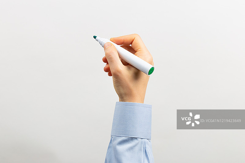 抬起的手臂用绿色记号笔在白板上书写图片素材