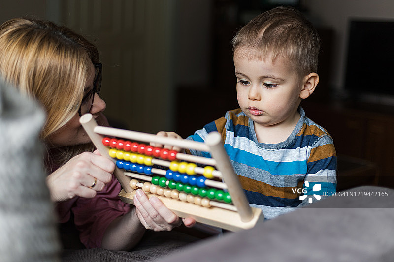 小男孩在慈爱的母亲手中玩玩具。图片素材