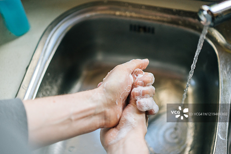 年轻男子在厨房水槽彻底洗手图片素材