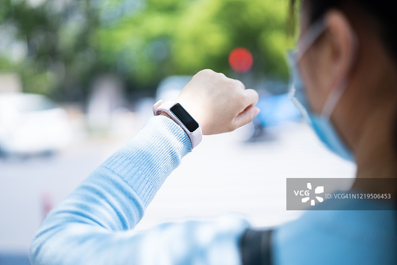 戴防护口罩使用智能手表的女人图片素材