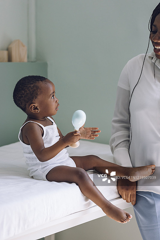 可爱的非洲裔美国女婴在诊所玩耍，等待检查图片素材