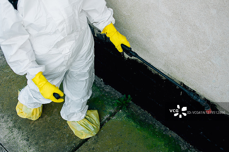 身穿防护服的女人在家中消毒喷洒图片素材