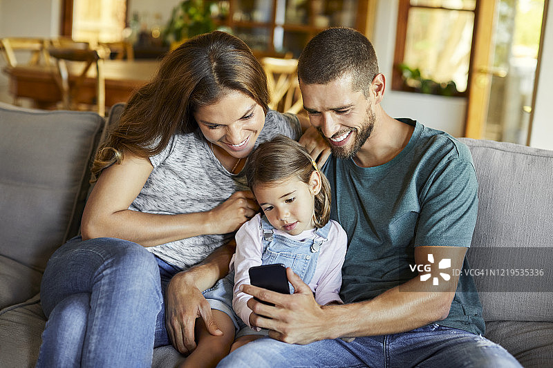 封锁期间，一家人在沙发上看手机图片素材