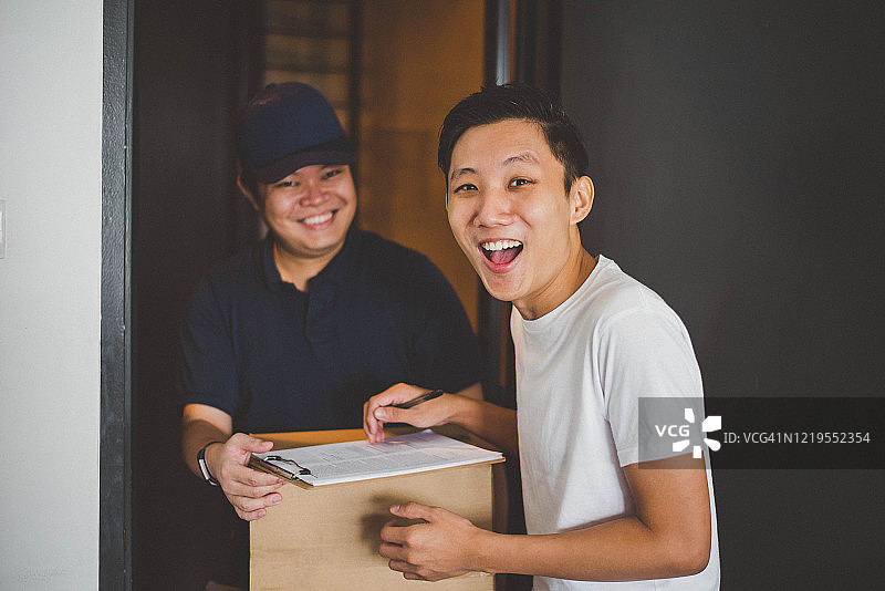 亚洲快递员向微笑的顾客送货图片素材