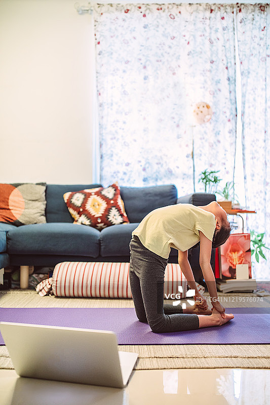 小女孩在家用笔记本电脑享受在线瑜伽课程图片素材