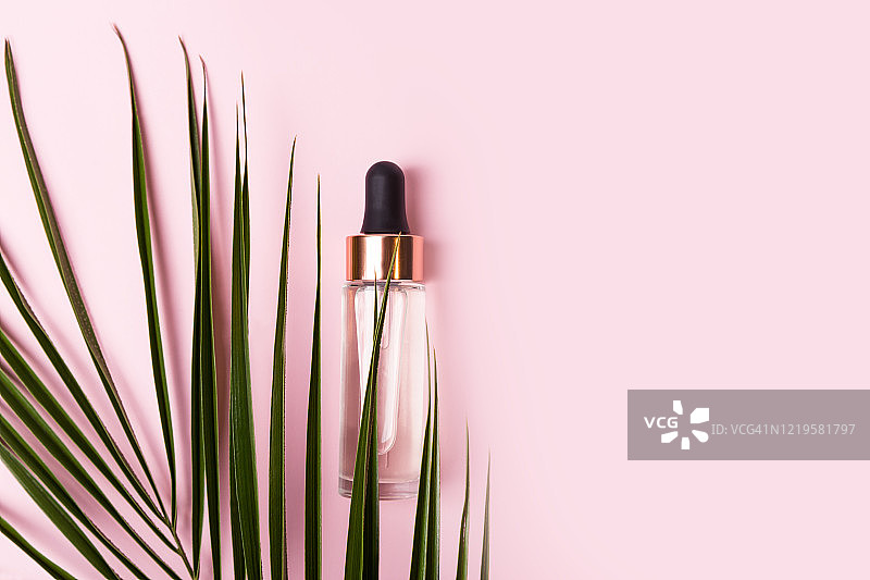 粉色背景下的精油玻璃瓶与滴管或面部精华图片素材