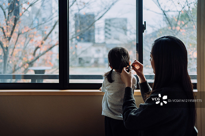 亚洲年轻母亲在家隔离期间照顾女儿，防止新冠病毒传播，祈祷疫情早日结束。图片素材