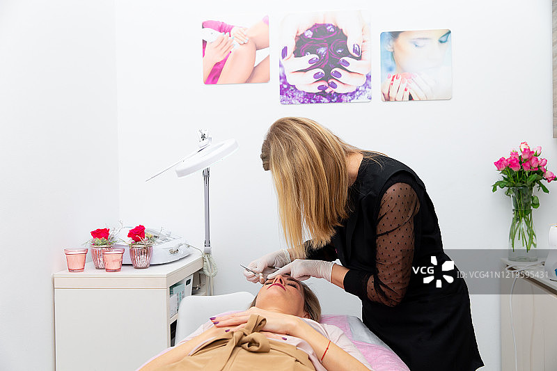 美容师在美容院用镊子修饰女士眉毛图片素材