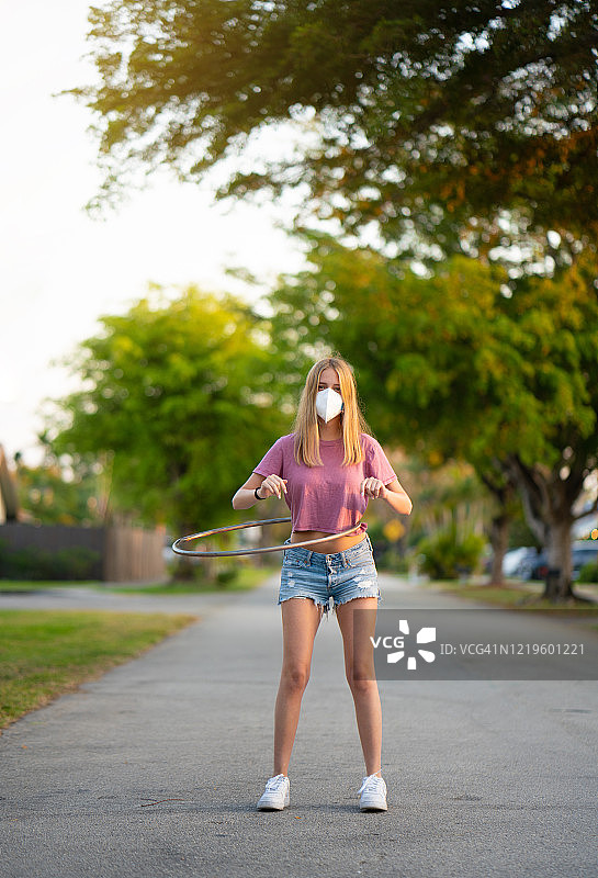 戴着口罩，转动塑料呼啦圈的少女图片素材