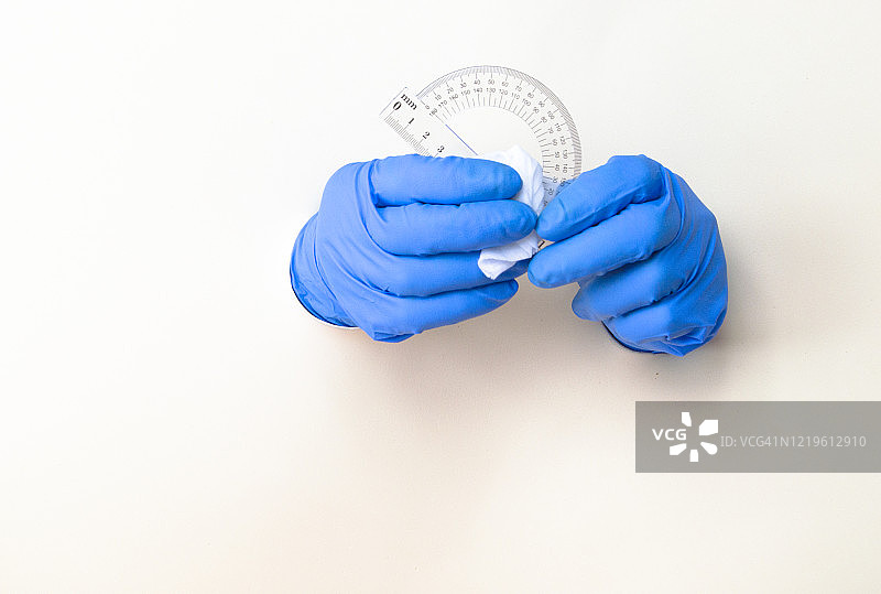 男人戴橡胶手套擦拭消毒量角器，预防新型冠状病毒（COVID-19）图片素材