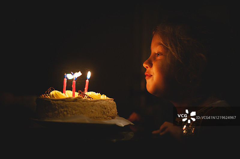 小女孩吹灭蛋糕上的蜡烛，生日快乐图片素材