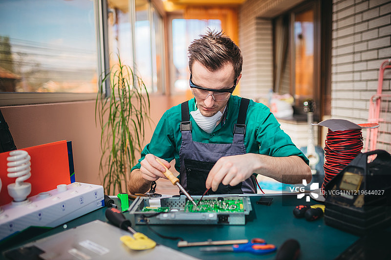 年轻电工在实验室维修电脑主板图片素材