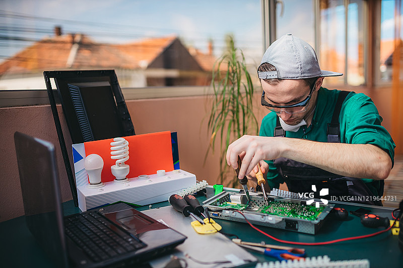 年轻电工在实验室维修电脑主板图片素材