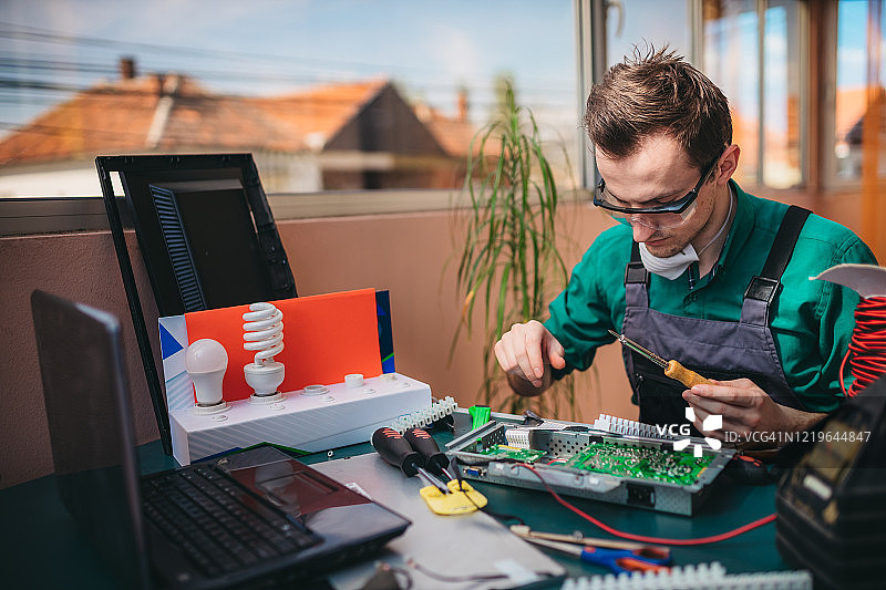 年轻电工在实验室维修电脑主板图片素材