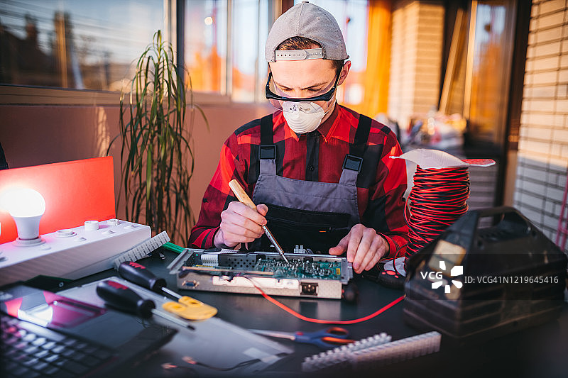 年轻电工在实验室维修电脑主板图片素材