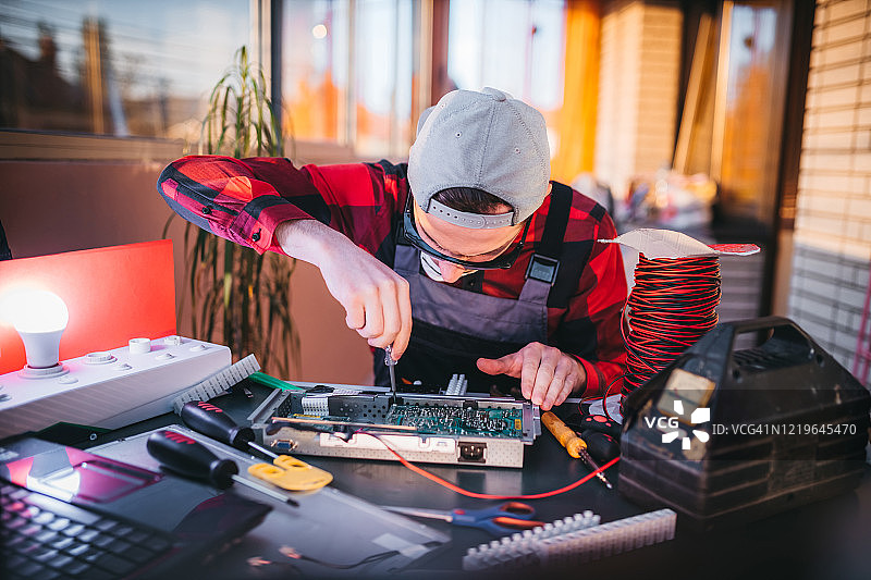 年轻电工在实验室维修电脑主板图片素材