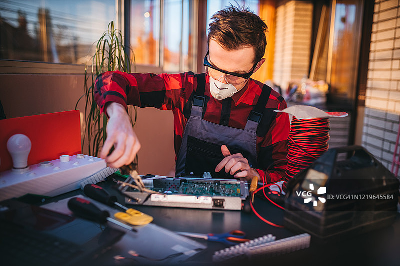 年轻电工在实验室维修电脑主板图片素材