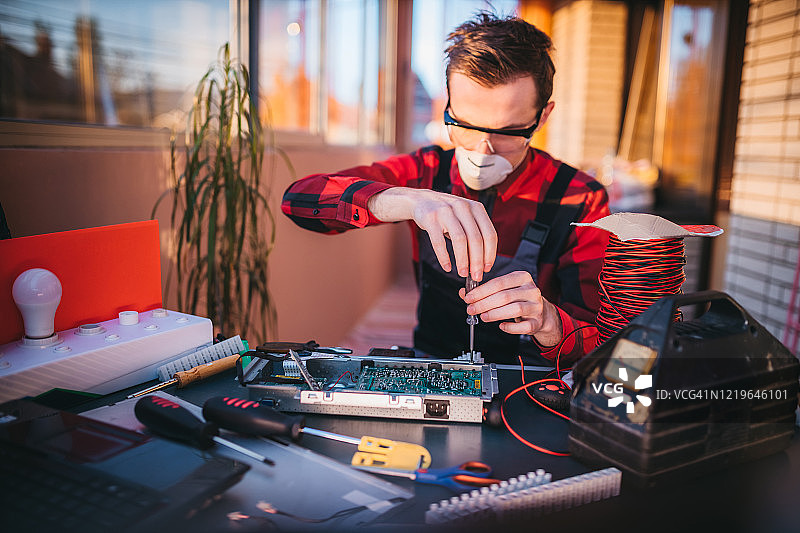 年轻电工在实验室维修电脑主板图片素材