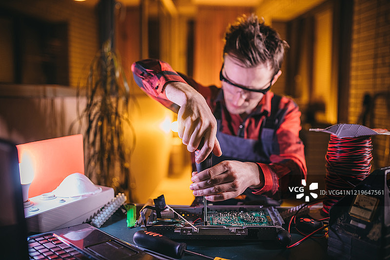 年轻电工在实验室维修电脑主板图片素材