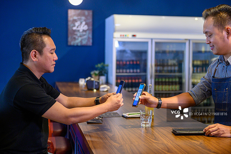 在吧台使用无线设备进行非现金数字钱包支付图片素材