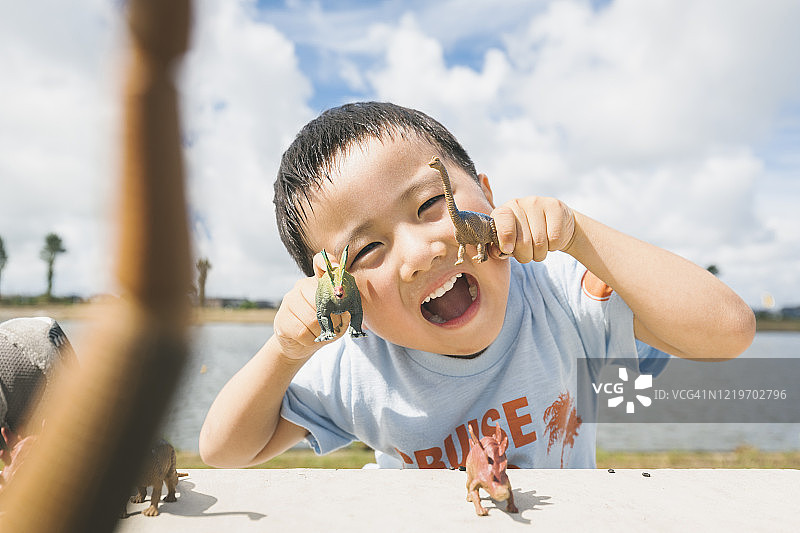 男孩在户外玩恐龙玩具图片素材