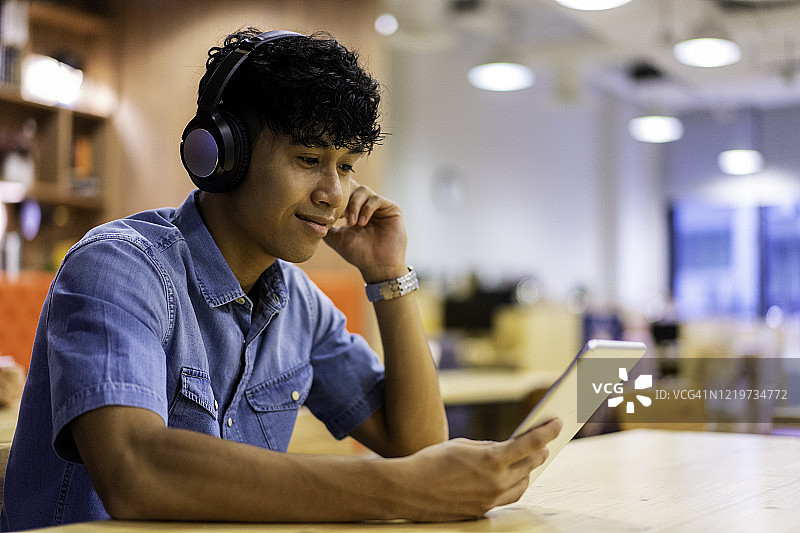 用平板电脑听播客的亚洲千禧一代图片素材