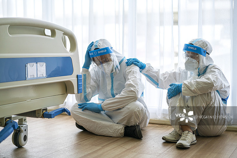 隔离病房里戴着N95口罩和防护服的两名疲惫的医生图片素材