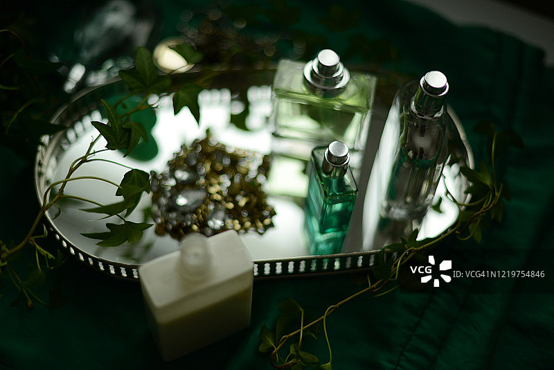 绿色背景的银色托盘上的三个香水瓶图片素材