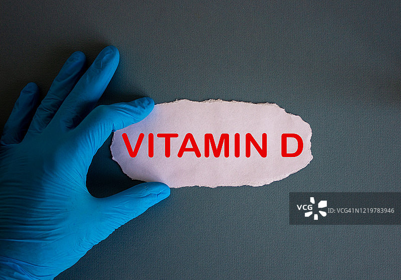 戴蓝色手套的手，拿着白色小纸片，维生素D概念图片素材