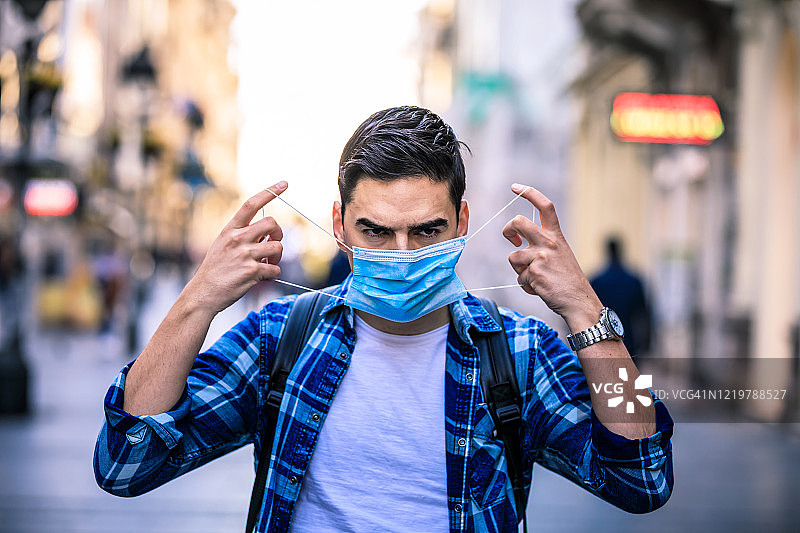 戴口罩的男人走在街上，预防病毒和流感图片素材