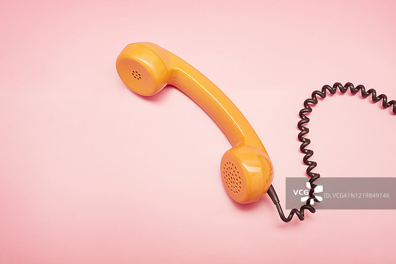 粉色背景上的橙色老式电话听筒高角度景观图片素材
