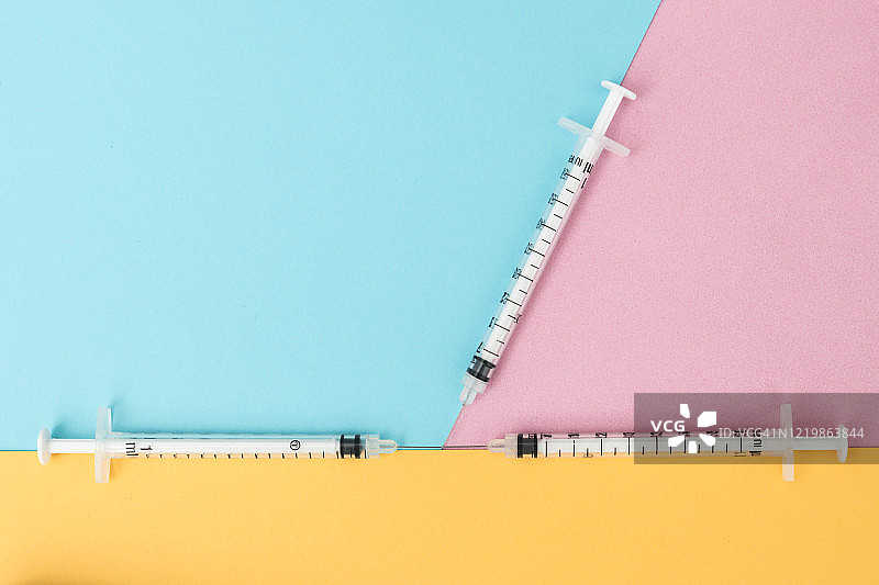 粉蓝黄背景上的三个注射器俯视图图片素材