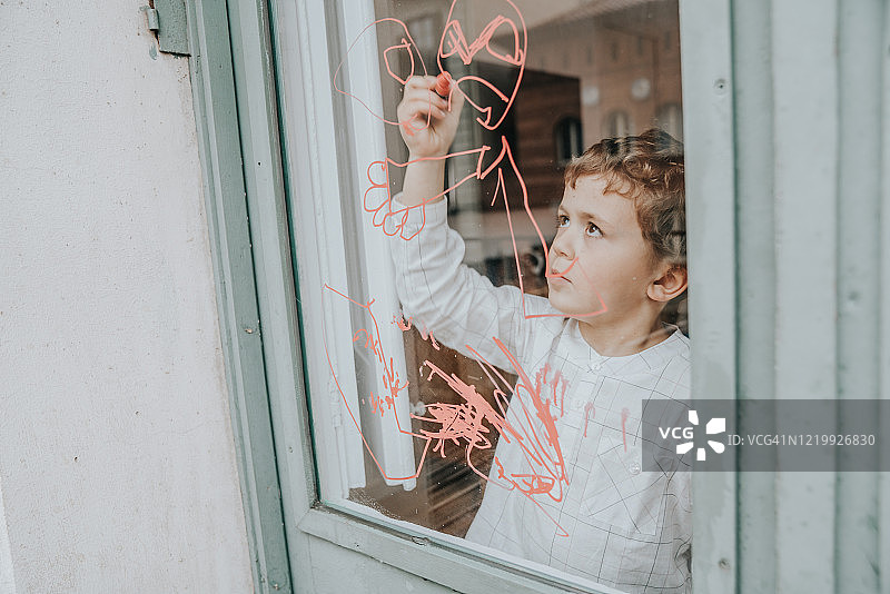 新冠疫情期间男孩在窗户上画画图片素材