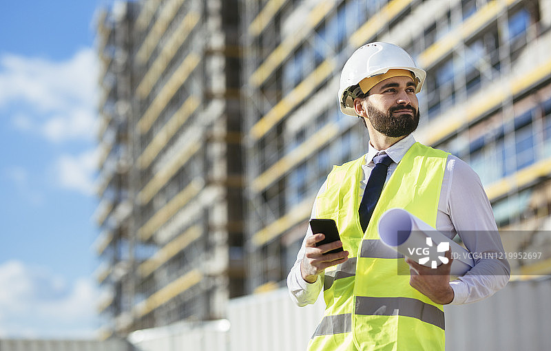 中年工程师拿着蓝图和手机图片素材