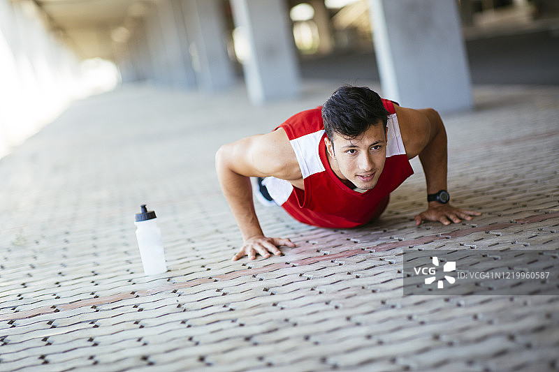 健壮男人在城市街道上做俯卧撑图片素材