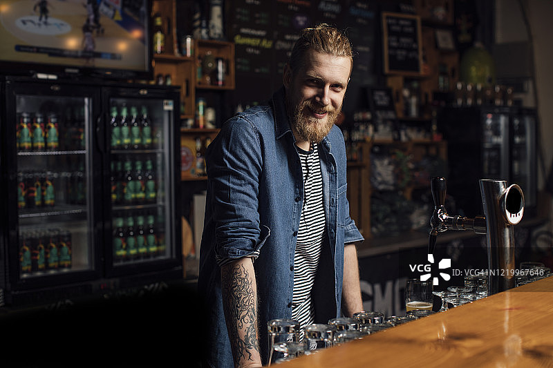 微笑的络腮胡金发时髦酒保的肖像图片素材