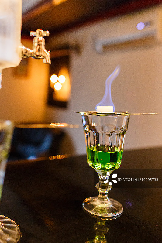 在漏勺上燃烧方糖以制备一份苦艾酒图片素材