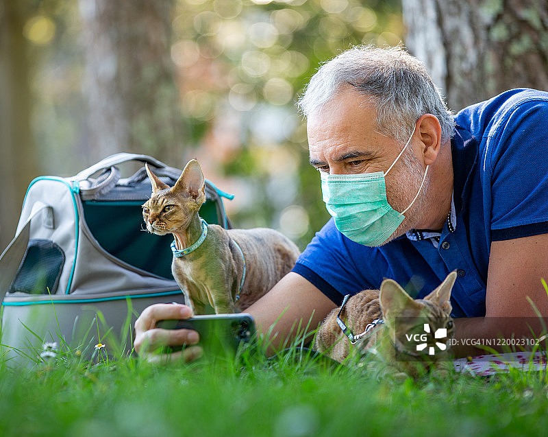 疫情期间在公园里与德文卷毛猫自拍的骄傲男人-库存照片图片素材